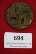 Commemorative Badge, a circular pressed-metal badge with raised design, central swastika in circle