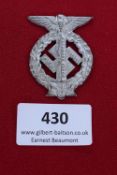 Kiel Rally Badge, 1935, a silvered alloy badge in the form of a swastika overlaid with sword,