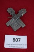 Double Horsehead Swastika Badge, a silvered pressed-metal badge depicting a stylised swastika