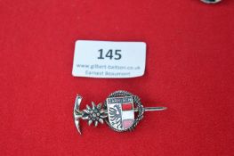 German souvenir/commemorative pin, featuring an edelweiss flower, ice axe, and the crest of