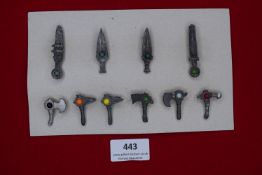 A German WWII WHW set of miniature weapons, pressed metal with coloured centres, including axes,