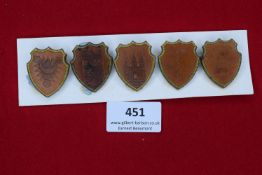 A German WWII WHW set of five miniature pressed-leather shield badges, each with impressed designs
