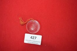 Glass Pendant – A circular clear glass pendant, etched with an ant motif, suspended from a red