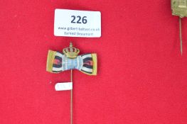 Pair of miniature bow ribbon stickpins, each topped with a crown device. One features yellow and