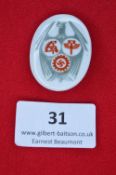 A German Third Reich porcelain day badge, oval white porcelain issue with grey eagle clutching three