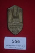 WHW tinnie badge, bronze finish, shield-shaped with twin spires, swastika, and text “Heimatfest