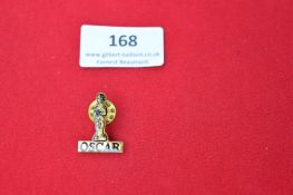 A novelty gilt lapel badge in the form of an Oscar statuette over the name “OSCAR”, fitted with