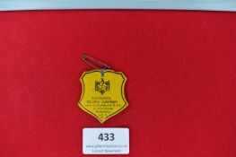 A yellow card badge in shield form, commemorating the 50th Anniversary Jubilee of the Turn-Verein