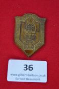 A German veterans’ rally badge, shield-shaped pressed alloy issue depicting sword over laurel wreath