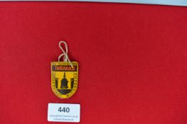 Printed Tin Plaque – A colourful tin plaque in the form of a shield, yellow with black printing.