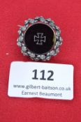 A German Honour Badge, circular silvered wreath enclosing a black enamelled medallion with inset