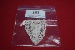 Delicate triangular white lace badge with ornate crochet-style edging, fitted with pin-back
