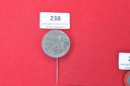 Commemorative Tinnie Badge “Tag Der Arbeit 1935” – A circular grey alloy badge with embossed eagle