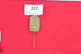 Bronze stickpin with an ornate arch-shaped design showing a central figure flanked by allegorical