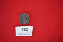 Pressed Metal Badge – A small circular pressed metal badge featuring the bust of a man in period-