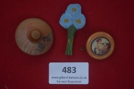 A group of three German WWII WHW day badges, comprising: a wooden hat badge painted with flowers;