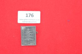 Rectangular grey badge with a Christmas tree and date “1916.” Reverse marked “DESCHLER & SOHN