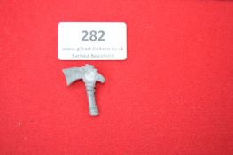 Cast Metal Commemorative Tinnie Badge in the form of a Medieval Axe – A grey-metal badge shaped as a