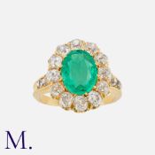 An Emerald And Diamond Cluster Ring in yellow gold, set with a principal mixed cut emerald, within a