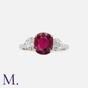 A Ruby And Diamond Three Stone Ring in platinum, set with a central cushion cut ruby of