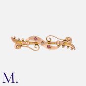 A Ruby and Diamond Brooch in 9K rose gold with a scrolling design. Hallmarked for 9ct gold. Metal