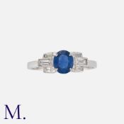 A Sapphire And Diamond Ring in white gold, set with a round cut sapphire accented by baguette cut