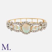An Opal And Diamond Bangle in 14k yellow gold, set with a central oval cabochon opal between a