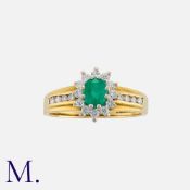 An Emerald and Diamond Cluster Ring in 18K yellow and white gold, set with an oval cut emerald