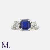 A Sapphire And Diamond Three Stone Ring in platinum, set with a central square step cut sapphire