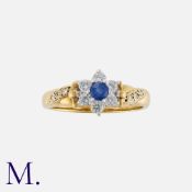 A Sapphire and Diamond Cluster Ring in 18K yellow gold, set with a round cut sapphire with six round