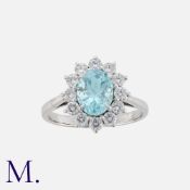 An Aquamarine And Diamond Ring in platinum, set with a central oval cut aquamarine within a border