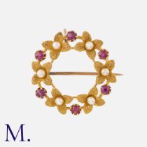 A Ruby And Pearl Wreath Brooch in yellow gold, of foliate, circular design, set with round cut