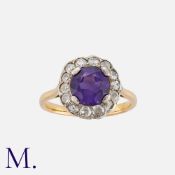 An Amethyst And Diamond Cluster Ring in yellow gold, set with a round cut amethyst within a border