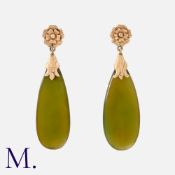 A Pair Of Green Stone Earrings in yellow gold. Each comprising a floral top suspending a polished