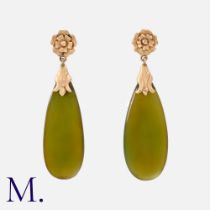 A Pair Of Green Stone Earrings in yellow gold. Each comprising a floral top suspending a polished