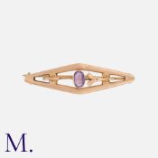 An Amethyst Brooch in 9K rose gold in rhomboidal form with an oval cut amethyst to the centre.