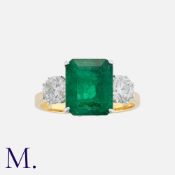 An Emerald And Diamond Three Stone Ring in 18k gold, set with a principal octagonal step cut emerald