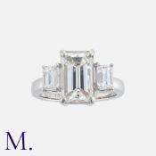 A Large Diamond Three Stone Ring in platinum, set with a principal emerald cut diamond of