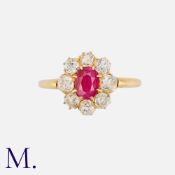 A Ruby And Diamond Cluster Ring in yellow gold, set with a central oval cut ruby of approximately