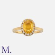 A Yellow Sapphire and Diamond Ring in 14k yellow gold, set with an oval-cut deep yellow-orange