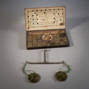 A COIN BALANCE WITH WEIGHTS IN A WOODEN BOX