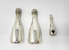 A PAIR OF VICTORIAN SILVER NOVELTY 'CHAMPAGNE BOTTLE' PEPPERETTES AND A CIGAR CUTTER