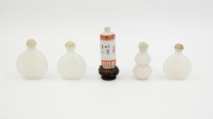 A composed lot of four various Chinese white jade snuff bottles and one porcelain snuff bottle