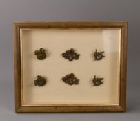 A framed selection of six Indonesian brass ear weights. Dayak people, Borneo. Three pairs.