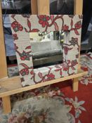 Woven reed mirror featuring an abstract red flower motif. Made from natural materials, this piece