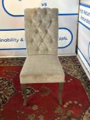 A grey velvet tufted scroll back chair with a high button back. It features studding and a silver