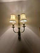 Traditional double-arm electric wall sconce with ribbon motif and fabric shades. Crafted from