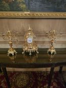 A three-piece gilt metal mantel garniture, comprising a central table clock and a pair of five-light