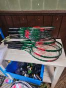 A collection of approximately 11 tennis racquets. The racquets predominantly feature green frames