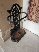 An ornate black-painted cast iron umbrella and stick stand, featuring an arched top with a central